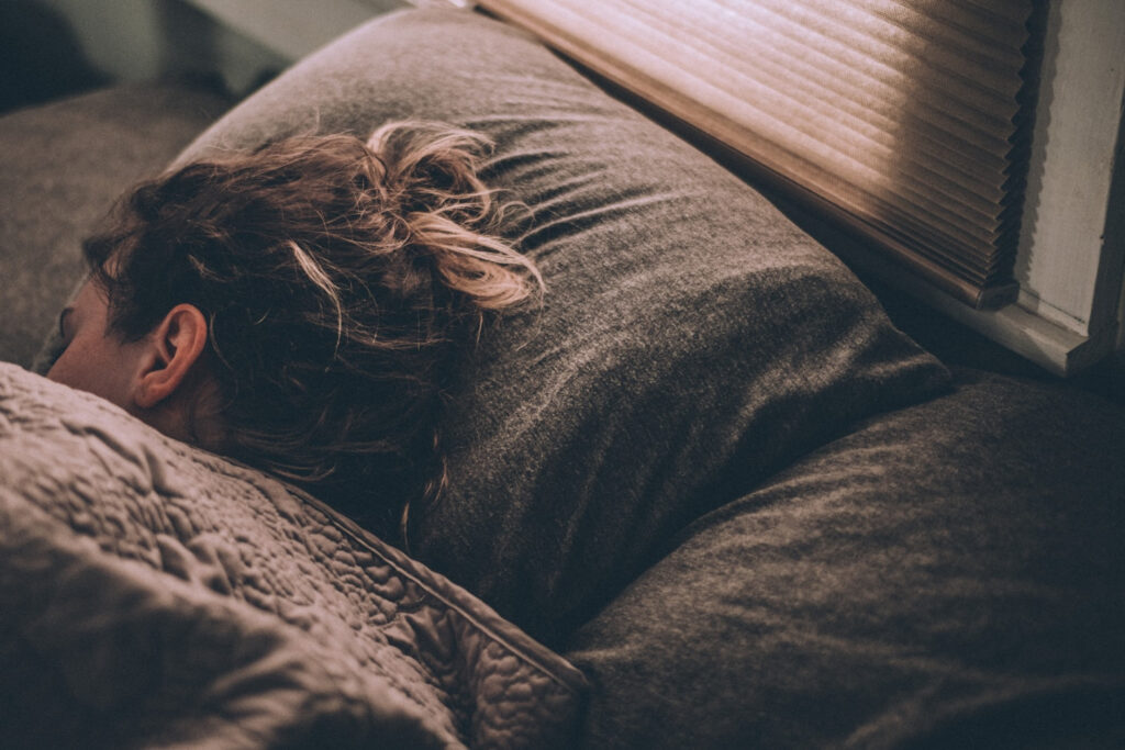 A person sleeping peacefully on a bed, representing restful sleep informed by sleep research.
